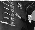 A sailor points out details of the Japanese trophy flags painted on Boise’s pilothouse as a scoreboard of enemy ships claimed sunk in the Battle of Cape Esperance, 11-12 October 1942.