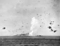 12 August 1942: Indomitable on fire after being bombed. HMS Charybdis is screening the carrier.